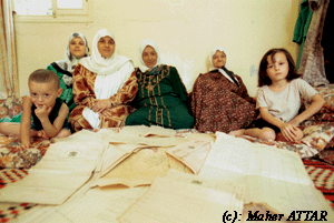 صورة لقرية طيطبا - فلسطين: : ثلاثة اجيال من عائلة الرفاعي (حميدة الاكبر عمراً) في مخيم عين الحوة ويظهر في المقدمة الكثير من اوراق الطابو التي تثبت ملكيتهم لاراضي طيطبة.